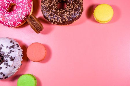 Fresh glazed donuts and French macaroons isolated on pink backgroundの写真素材
