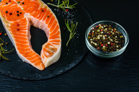 Raw salmon steak and spices on slate boardの写真素材