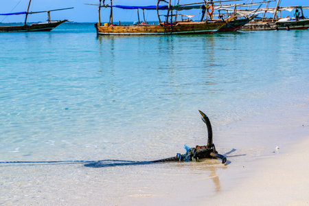 Iron anchor on sand at beach. Boats at background. Zanzibar, Tanzaniaの写真素材