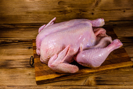 Wooden cutting board with whole uncooked chickenの写真素材