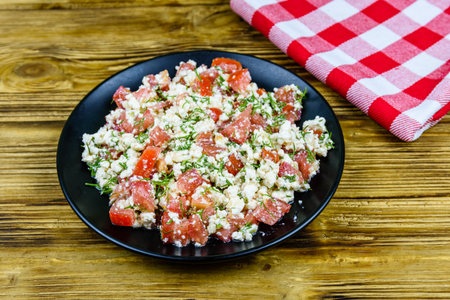 Salad with tomatoes, cottage cheese, dill and olive oil on wooden tableの写真素材