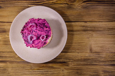 Ceramic plate with russian traditional new year salad herring under fur coat (shuba) and on rustic wooden table. Top viewの写真素材