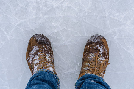 Men boots on cracked ice. Winter conceptの写真素材