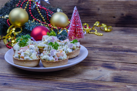 Tartlets with new year salad olivier on wooden table. Christmas decorations on backgroundの写真素材