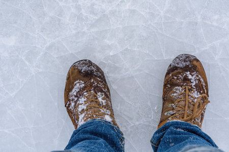 Men boots on cracked ice. Winter conceptの写真素材