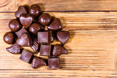 Heap of chocolate candies on wooden table. Top view