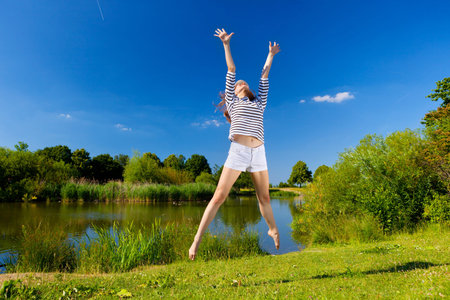 pretty young woman jumping on green grassの写真素材