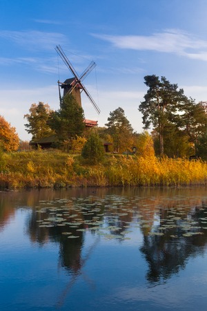 Old wooden windmill in autumn's environment  over the riverの写真素材