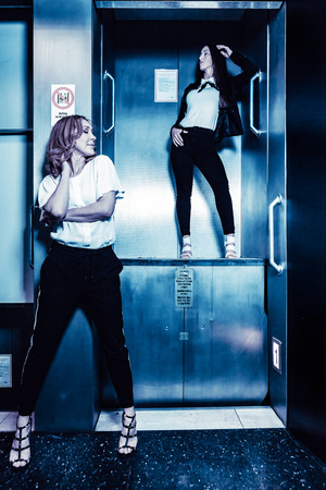 Dark color toned picture of two fashionable sexy girl in the elevator.の写真素材