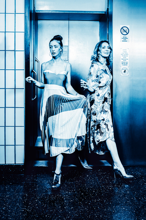 Dark color toned picture of two fashionable sexy girl in the elevator.の写真素材