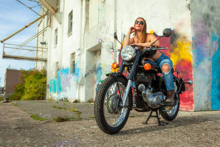 An attractive girl on a motorbike posing outside