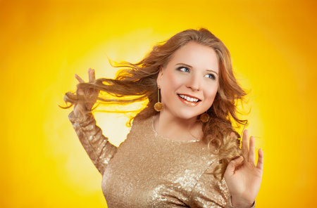 Beautiful fashionable young blonde woman in a studio. Yellow background.の写真素材