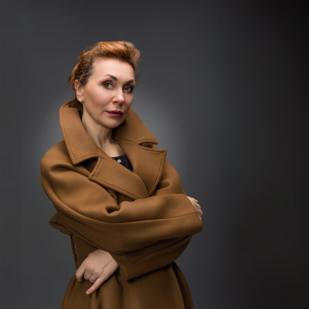 A refined portrait of a sophisticated woman in a luxurious brown coat. The soft lighting enhances her grace, blending classic fashion and poise.の写真素材
