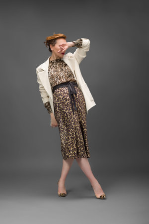 Confident woman in leopard print dress, fashion studio portrait