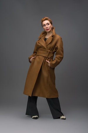 Elegant woman in brown coat posing in studioの写真素材
