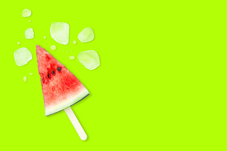 Slice of watermelon with ice cubes on a green background. Ice cream with the taste of watermelon. Sweet dessert. The summer mood.の写真素材