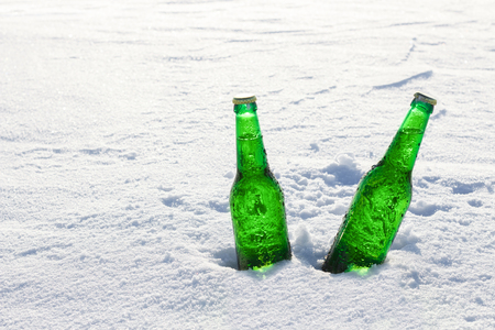 Two bottles of cold beer on the snow at sunset. Close up view.の写真素材