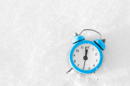 Vintage alarm clock on the snow at sunset. The concept of Christmas and New Year. Magic composition....