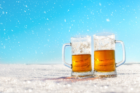 Two mugs of cold beer on the snowの写真素材