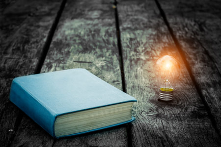 Old tattered book on a wooden table. Reading by candlelight. Vintage composition. Ancient library....