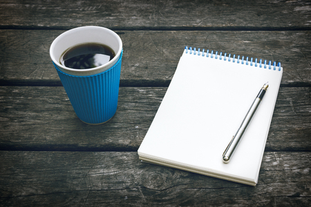 Cup of hot coffee, pen and notepad, blank sheet of paper on the old wooden background. Business plan. Writing poetry.の写真素材