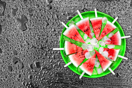 Slice of watermelon with ice cubes on a black background. Ice cream with the taste of watermelon. Sweet dessert. The summer mood.の写真素材