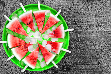 Slice of watermelon with ice cubes on a black background. Ice cream with the taste of watermelon. Sweet dessert. The summer mood.の写真素材