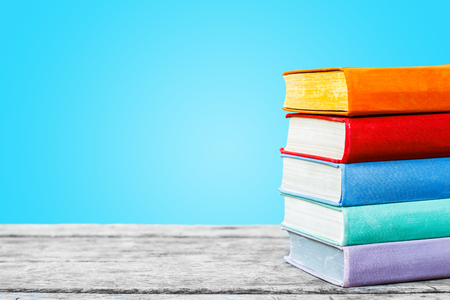 Books on the old wooden table on the blue background. Concept: back to school, education.の写真素材