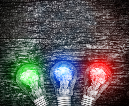 Burning light bulbs on dark old wooden background. New business idea and innovation in trade. Selling, buying and advertising. Environmentally friendly energy sources. Alternative forms of energy.の写真素材