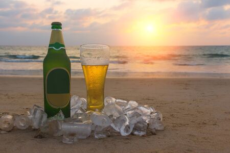 Glass of cold beer on the sea shore at the sunset. Relax on the beach.の写真素材