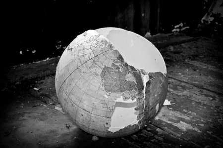 Globe on old wooden floor. Global warming concept. Black and white. Broken globe on a wooden floor, black and white photo. Global warming conceptの写真素材