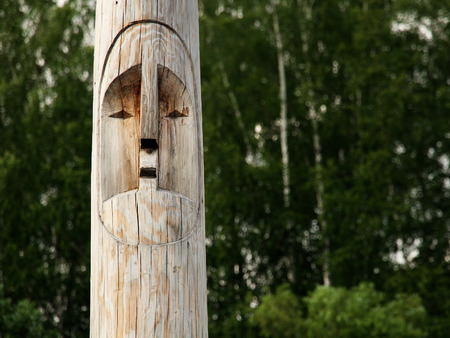 Wooden totem idol pole with a forest as a background.の写真素材
