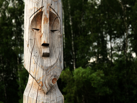 Wooden totem idol pole with a forest as a background.の写真素材