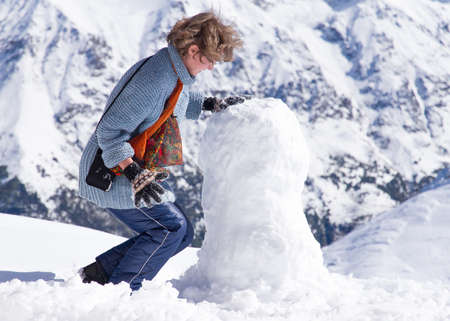 Nice looking pretty blondy caucasian happy cheerful successful girl staying at the top of mountain covered by snow and making snowman.
Photo taken on: September 30th, 2014 の写真素材