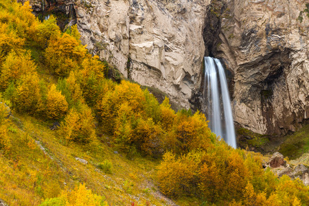 Autumn landscape: mountain stream and waterfall surrounded by stones, rocks and trees with yellow foliage.の写真素材