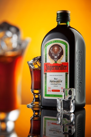 Jagermeister bottle with glasses and cube ice. Studio shot with reflaction. Yellow background. Ukraineのeditorial素材