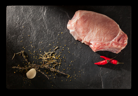 Raw fresh meat with herbs and spices on stone slate plateの写真素材