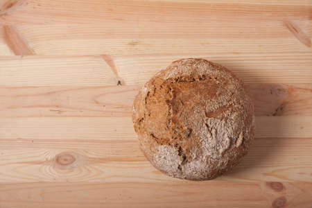 Handmade fresh wheat bread on wooden background in the morning light.の写真素材