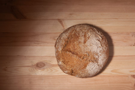 Handmade fresh wheat bread on wooden background in the contrast light. horizontal frame top view...