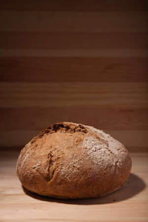 Handmade fresh wheat bread on wooden background in the contrast light. vertical frame side view with space area for text or designの写真素材