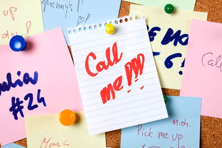 Note saying "call me" pinned on notice boardの写真素材