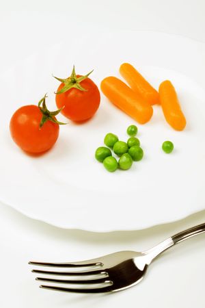 Tomato green peas and carrot served on a plateの写真素材