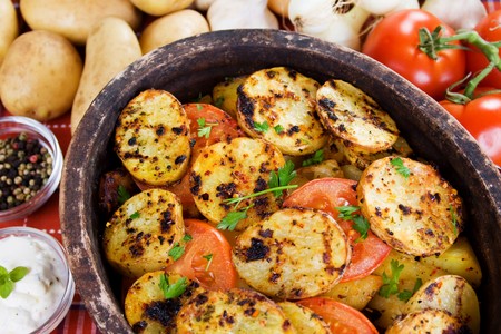 Roasted slices of potato in rustic clay potの写真素材