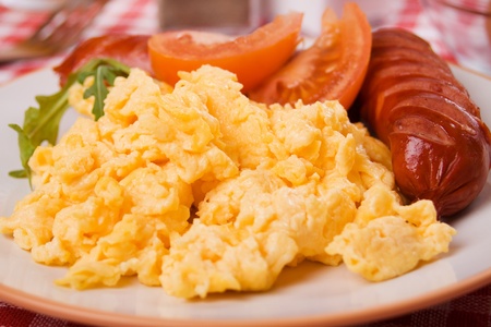 Scrambled eggs served with sausage and tomato for rich nutritive breakfastの写真素材