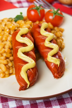 Grilled sausage served with mustard and cooked beansの写真素材