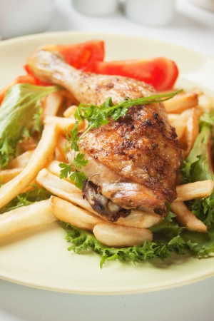 Roasted chicken leg with french fries, lettuce and tomatoの写真素材
