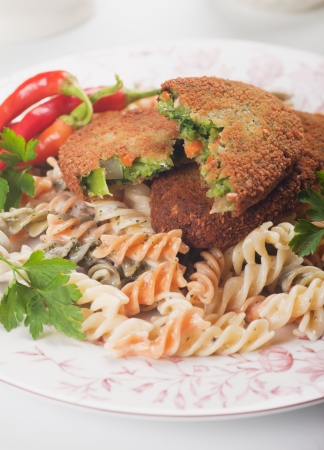 Breaded vegetable steak or burger with pasta tricoloreの写真素材