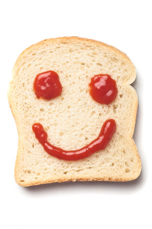 Happy smiley made from ketchup and slice of bread, isolated on white backgroundの写真素材
