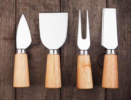 Set of cheese knives and fork on wooden tableの写真素材