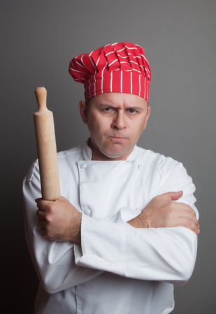 Angry chef with rolling pin, studio shot over gray backgroundの写真素材